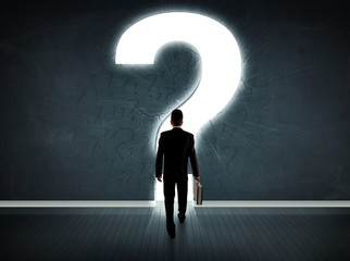 Obraz premium Business man looking at wall with a bright question mark
