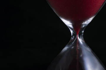 Close up of red hourglass on black background