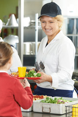 Famale Pupil In School Cafeteria Being Served Lunch By Dinner La