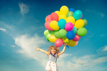 Child with toy balloons in spring field