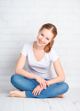 happy young woman is sitting in room with blank wall