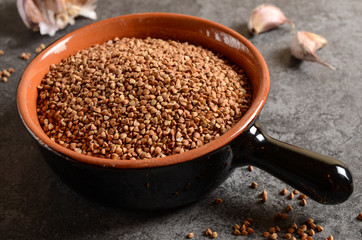 Buckwheat in a bowl with garlic on a stone background