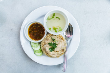 Rice roast chicken with spoon and fork on white plate.