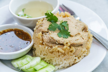 Rice roast chicken with spoon and fork on white plate.