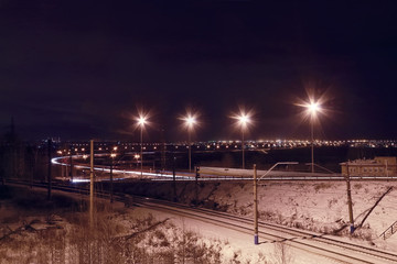 Night view of railroad with lanterns and lights of city 