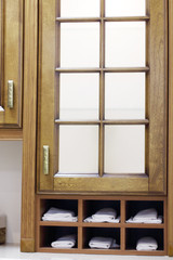 Stylish wooden cupboard with shelves with white towels