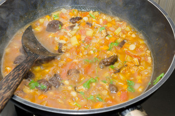 cooking pasta with chicken and meat gravy on stove