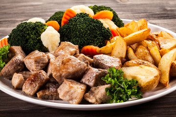 Grilled meat with baked potatoes and vegetables
