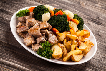 Grilled meat with baked potatoes and vegetables
