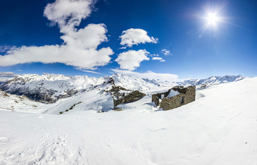 Fototapeta na wymiar Panorama invernale in montagna con ruderi in pietra
