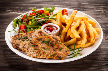 Fried steaks, French fries and vegetables