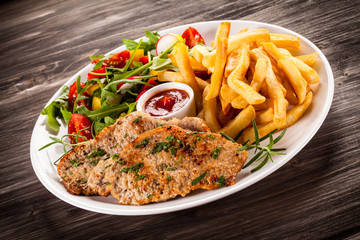 Fried steaks, French fries and vegetables