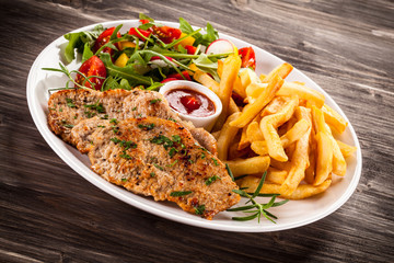 Fried steaks, French fries and vegetables