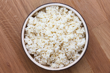 Cooked quinoa in a ceramic bowl on wood table.