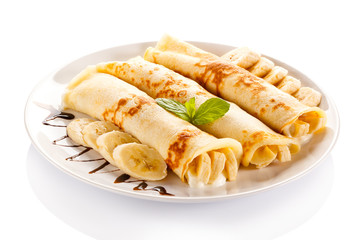 Crepes with bananas and cream on white background