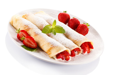 Crepes with strawberries and cream on white background