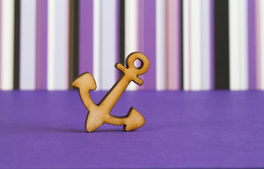 Wooden icon of anchor on purple striped background