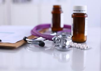 Doctor's stethoscope  with folder and bottle of pills on the