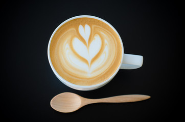 a cup of latte art on black background
