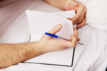 Man writing a note in bed.