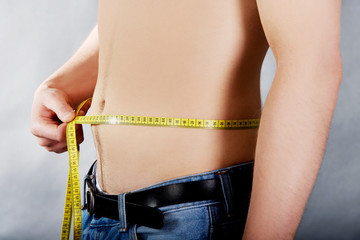 Young man measuring waist.