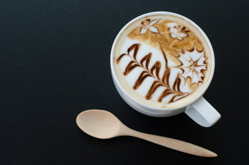 a cup of latte art on black background
