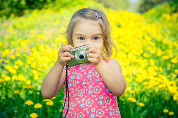 Little girl taking pictures on a meadow