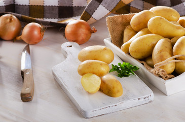 Fresh organic potatoes on  white wooden board