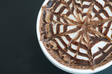 a cup of latte art on black background