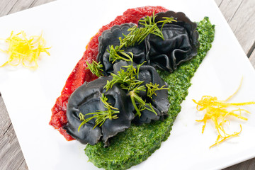 Black ravioli with spinach and garlic sauce tomato.