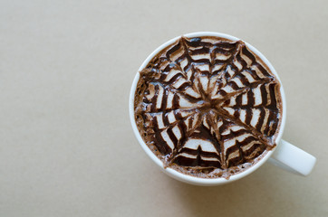 a cup of coffee with latte art on brown paper background