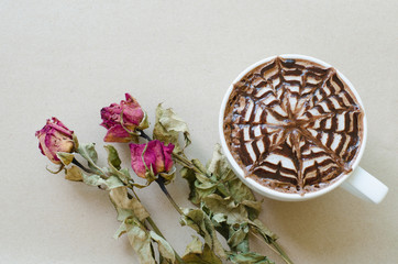 A cup of coffee with latte art and wither rose on brown paper ba