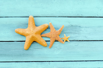 Fototapeta na wymiar Three starfish on a blue wooden background