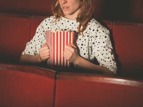 Young woman clutching popocorn in cinema