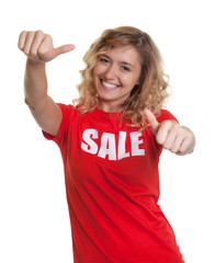 Blonde Frau im Sale-Shirt zeigt beide Daumen