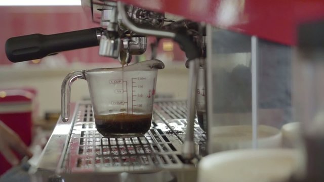 Fresh roasted coffee are being squeezed into a measuring cup