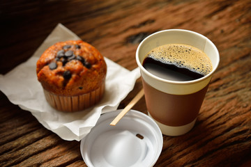 Paper cup of coffee and cake on wooden background