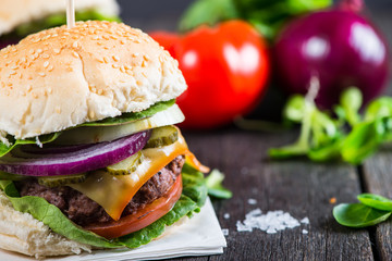 Homemade burger with vegetables on wooden table