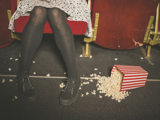 Woman in theater with popcorn on the floor