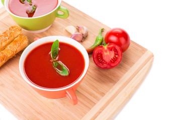 Bowl of tomato soup on wood platter.