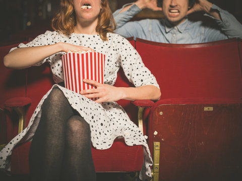 Woman annoying man in cinema by eating popcorn