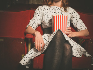 Young woman sitting in movie theater with popcorn