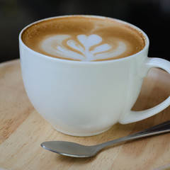 a cup of latte art on wooden plate