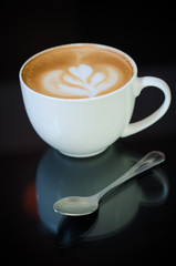 a cup of latte art on black background