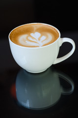 a cup of latte art on black background