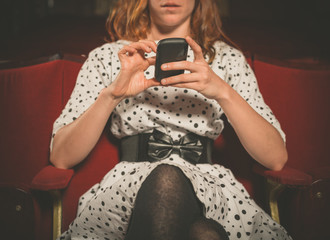 Young woman on front row of movie theater using her phone