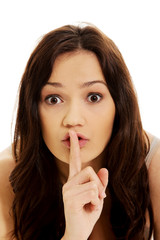 Naklejka premium Young woman with finger on lips.