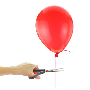 Scissors about to cut loose a balloon isolated on white