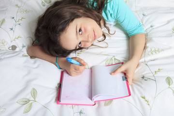 Girl writing diary in bed