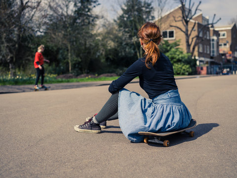 Woman sitting on skateboard in the park